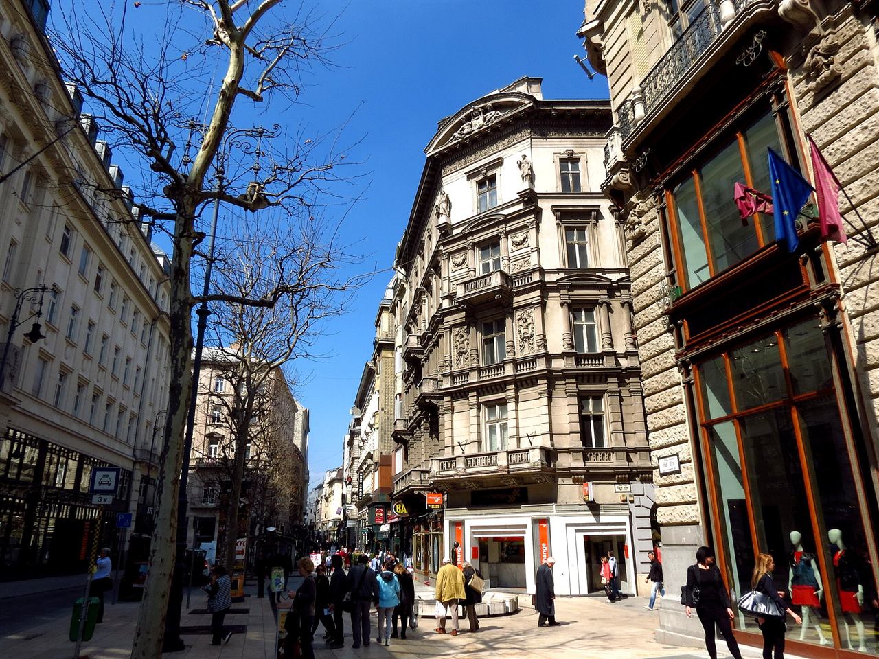 Street-level view of Vaci utca in Budapest with pedestrians walking past shopfronts on the cobbled pedestrian street